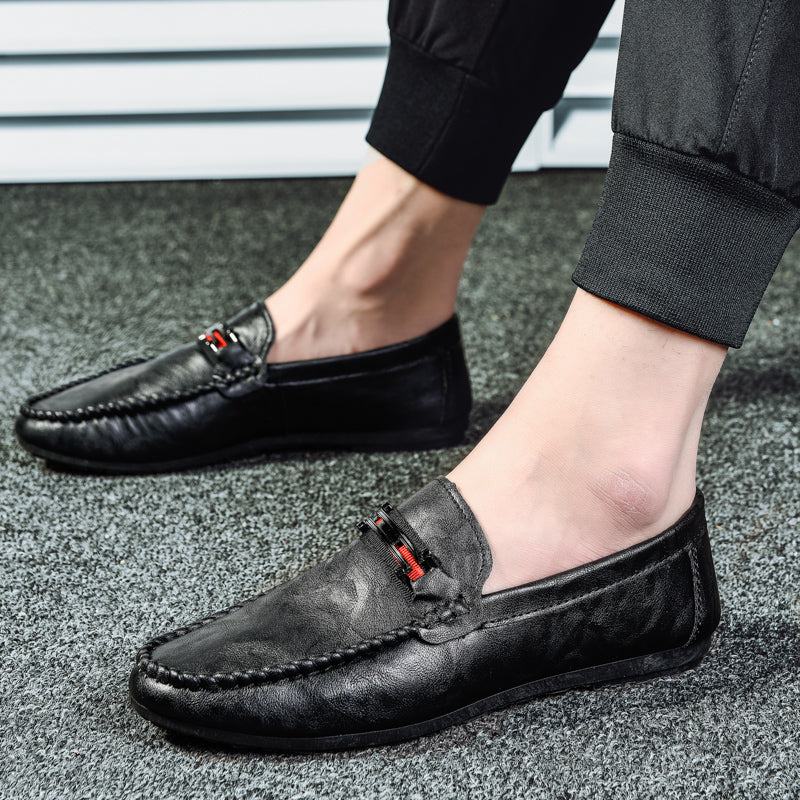 Black moc-toe slip-on loafers with red/gray strap detail and stitched upper