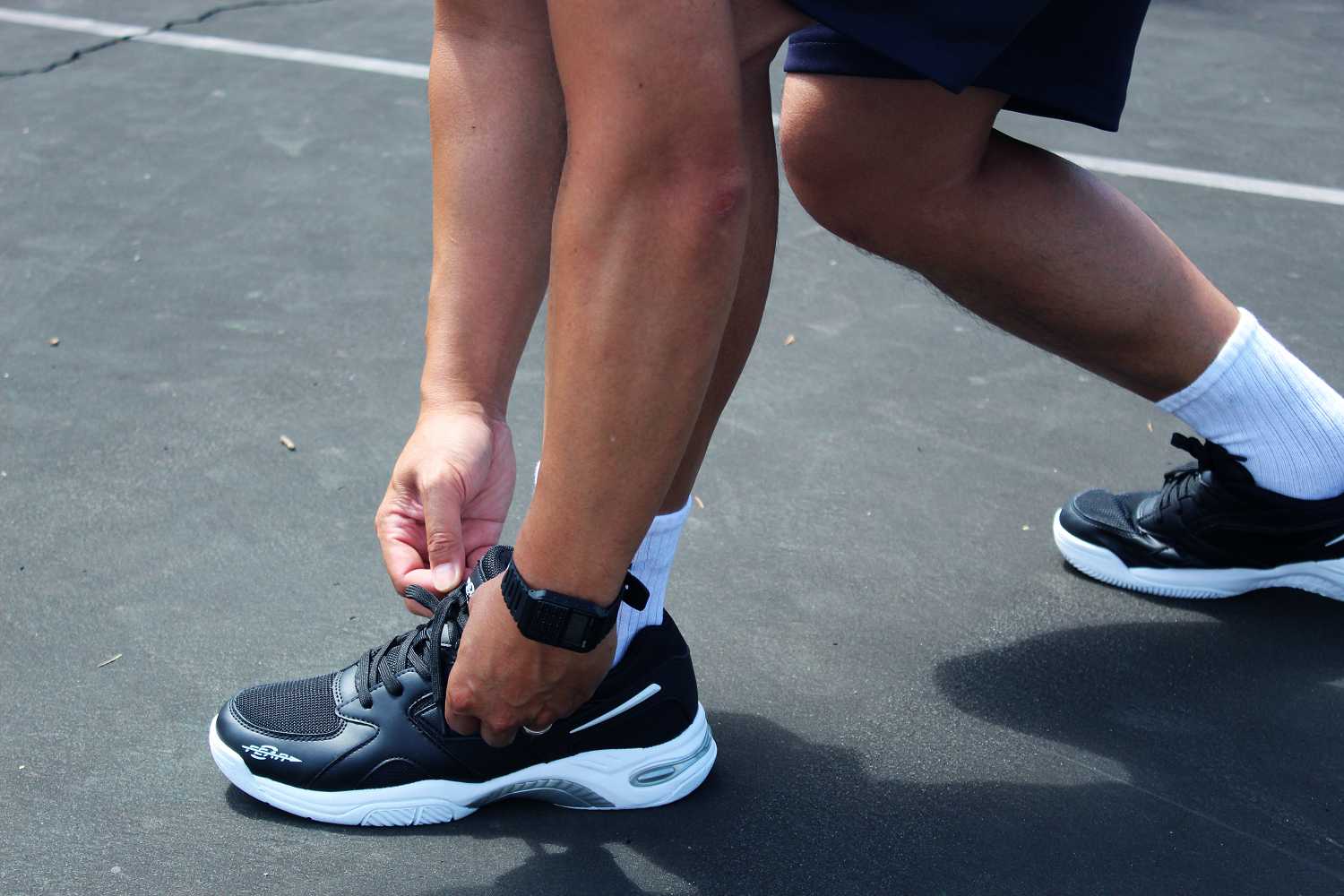 Men's structured walking sneakers in dark color worn while walking outdoors