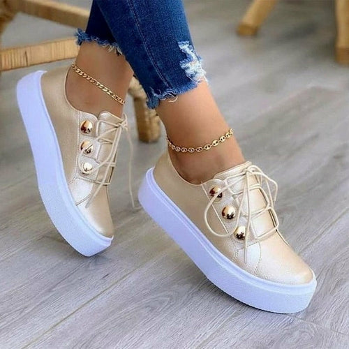 Light beige platform sneakers, lace-up front with gold toe studs, gold ankle chain