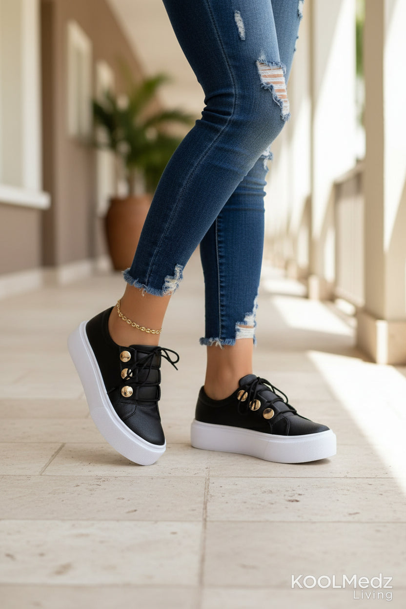 Black platform sneakers with lace-up front, gold ankle chain, metallic toe studs