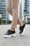 Black glossy platform lace-up shoes with thick white lug soles and lace-up front