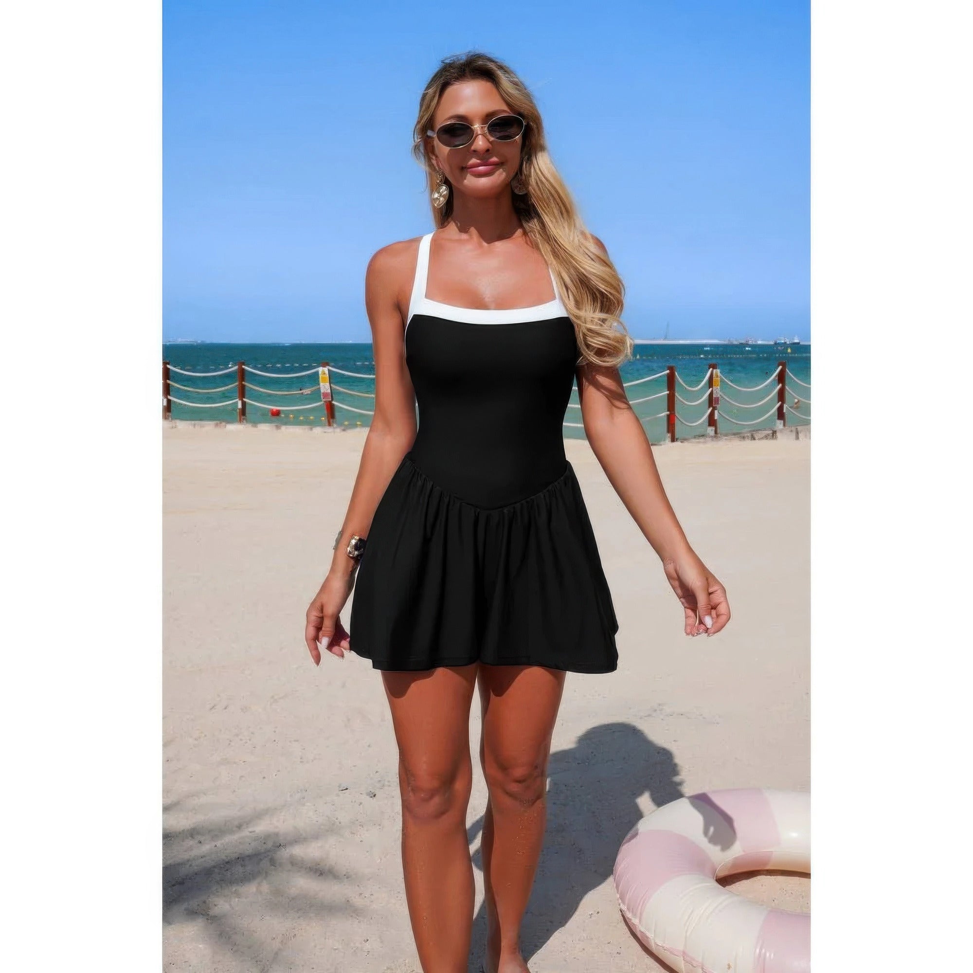 Black sleeveless one-piece swimsuit romper with flared skirt and white bust trim