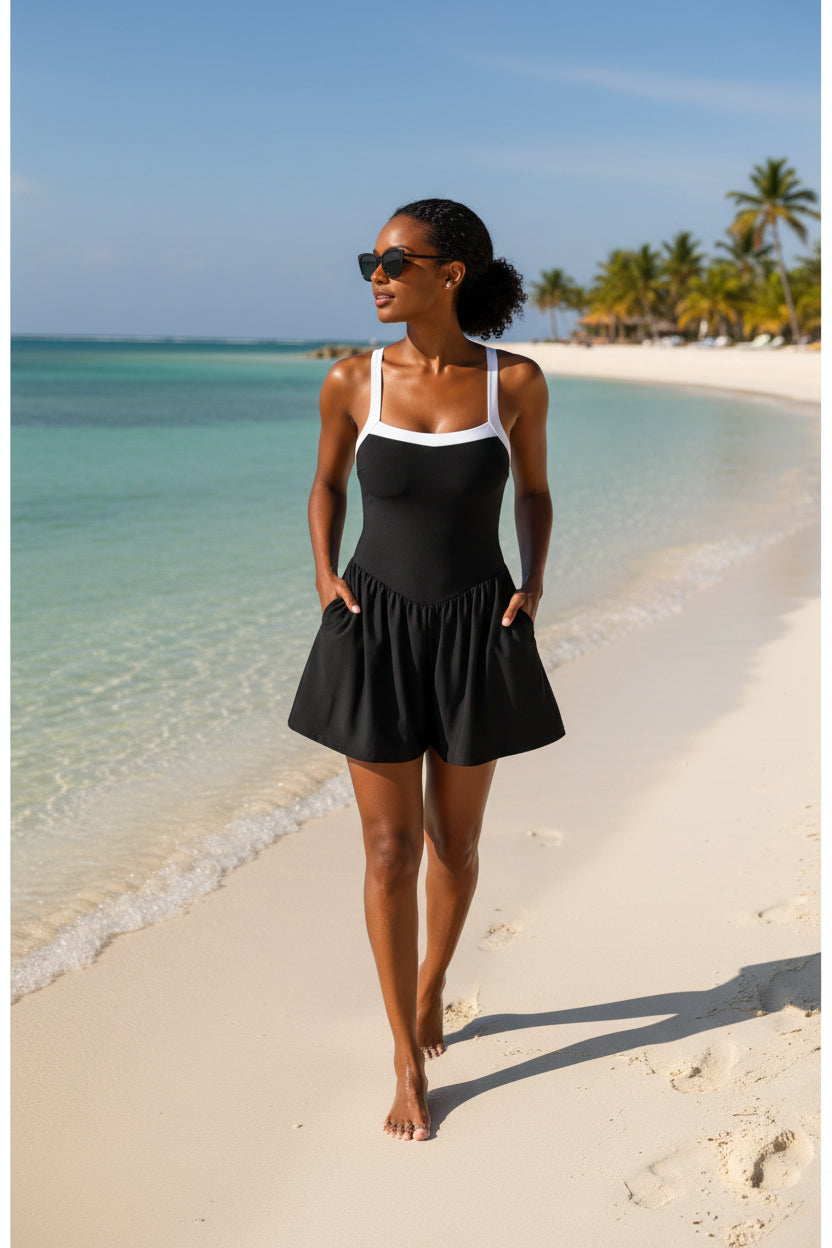 Black one-piece swimsuit romper with flared skirt and white scoop neckline