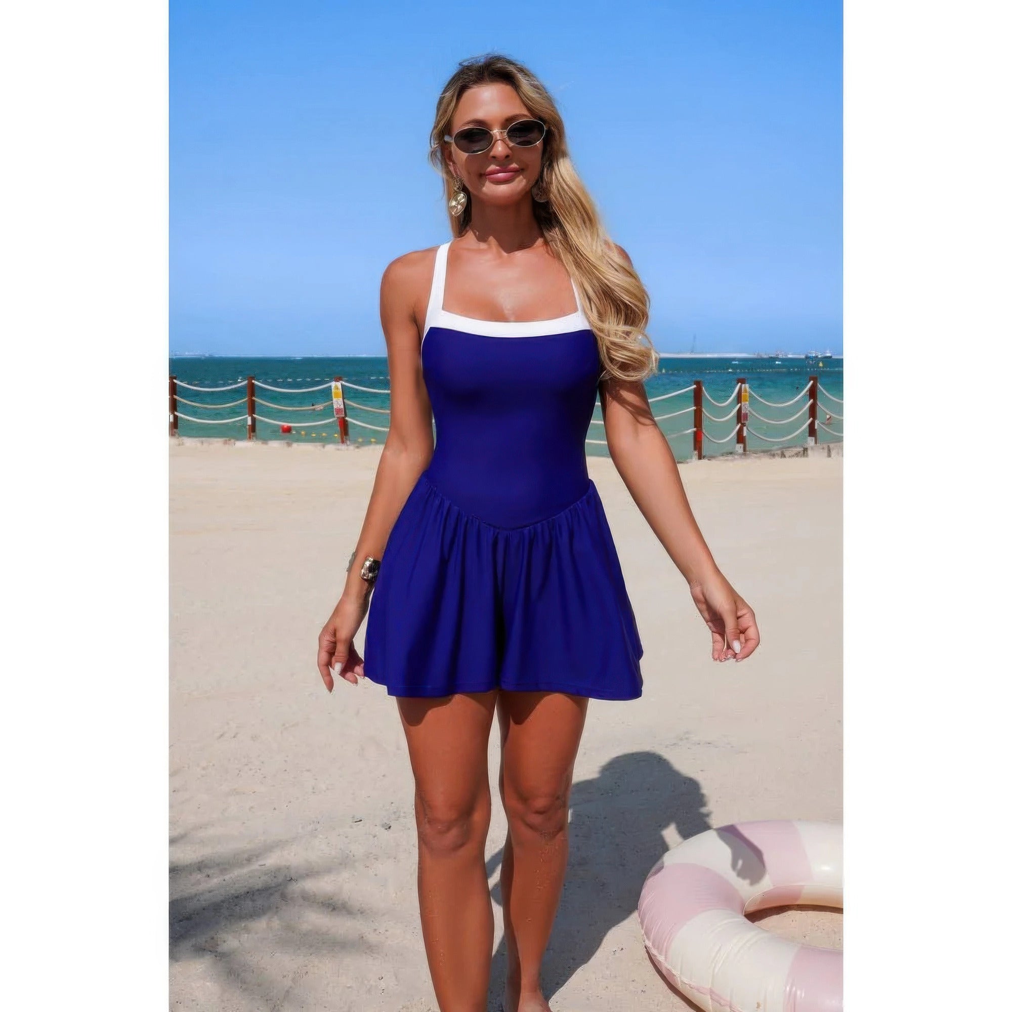 Navy sleeveless one-piece swimsuit romper with gathered skirt and white neckline band