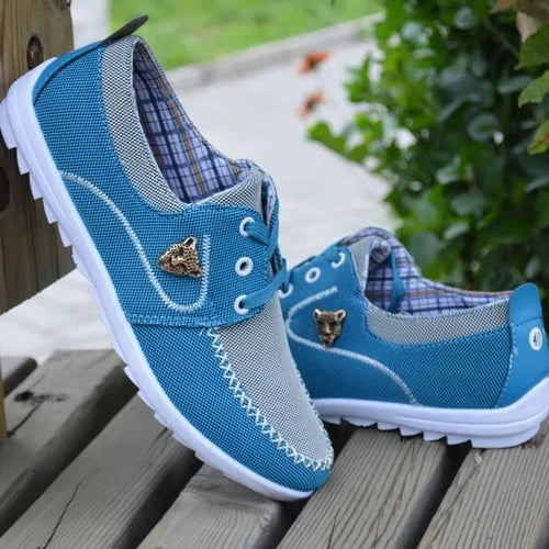 Pair of men's flat canvas sneakers in light blue, lace-up side view with white sole