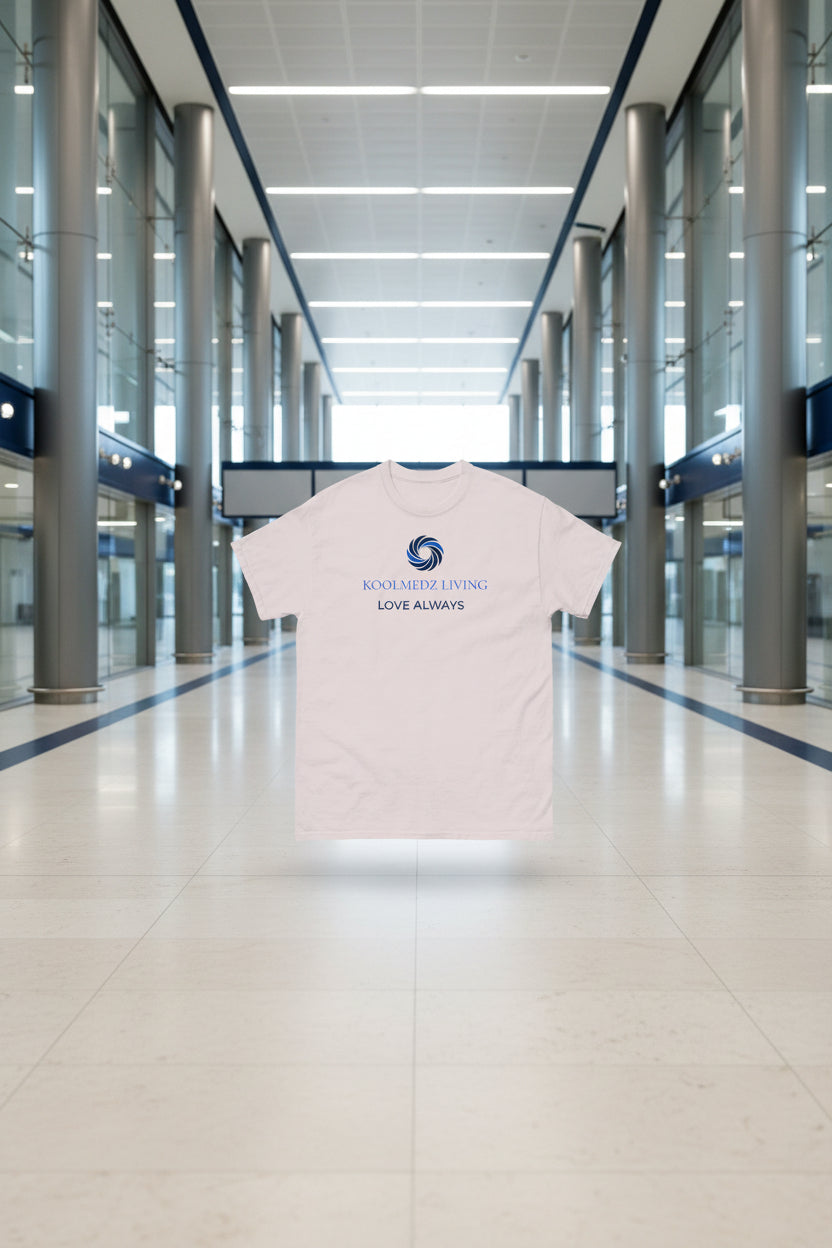 A light beige crewneck t-shirt with a blue and navy graphic on the chest featuring a swirl logo and the text 'KOOLMEDZ LIVING' and 'LOVE ALWAYS'.