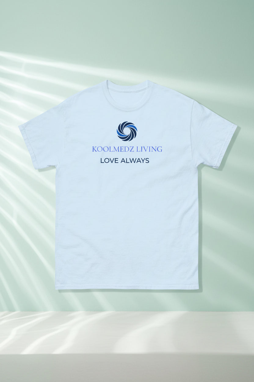 A light blue short-sleeve crewneck t-shirt with a blue and navy graphic on the chest featuring a swirl logo and the text 'KOOLMEDZ LIVING' and 'LOVE ALWAYS'.