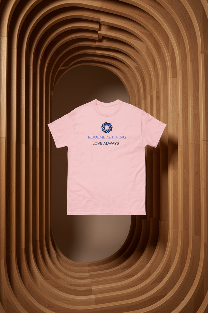 A light pink short-sleeve crewneck t-shirt with a blue and navy graphic on the chest. The graphic features a circular swirl logo above the text 'KOOLMEDZ LIVING' in blue and 'LOVE DEEPLY' in navy, displayed on a clean white background.