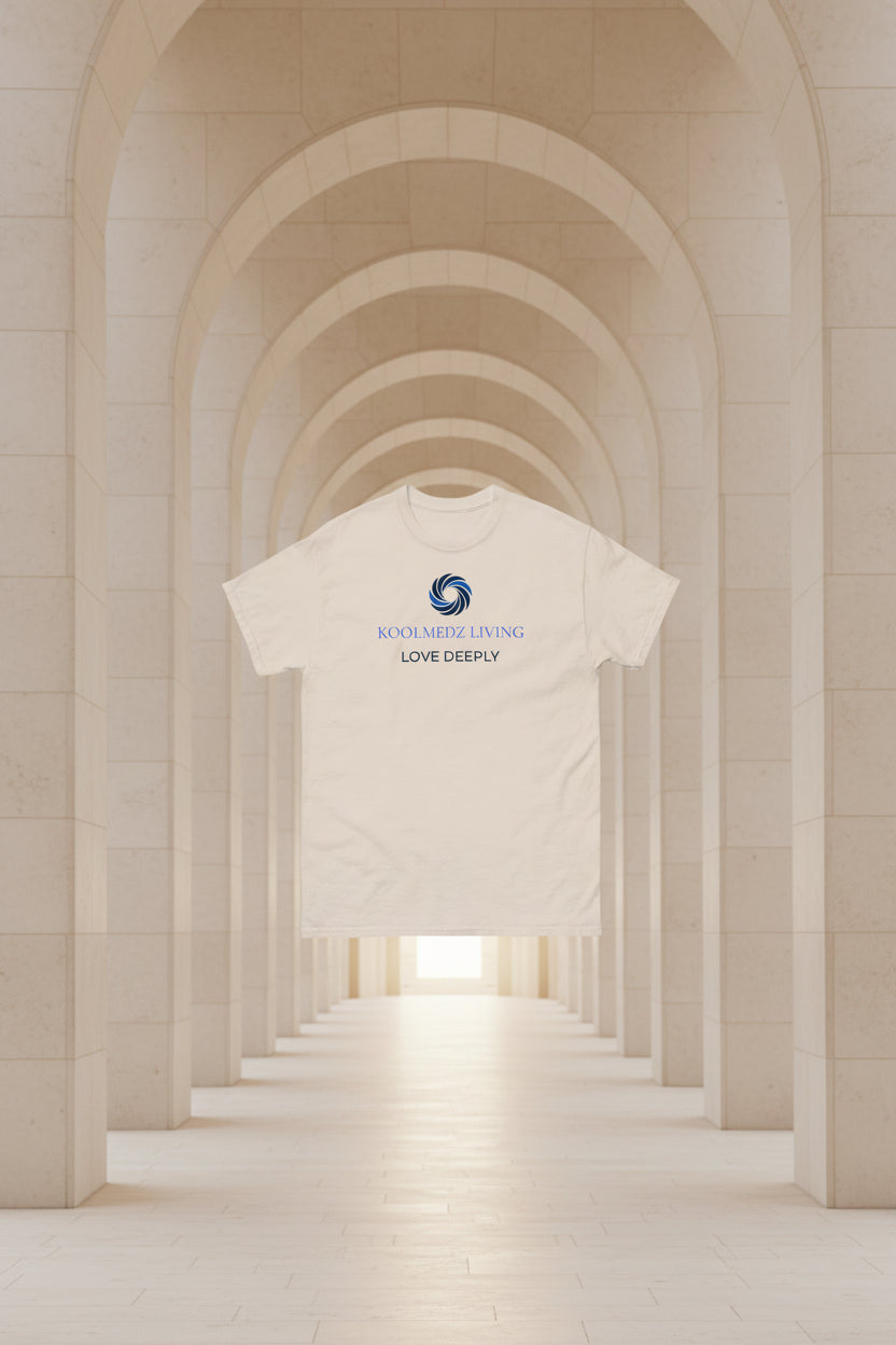 A light beige crewneck t-shirt with a blue and navy graphic on the chest featuring a swirl logo and the text 'KOOLMEDZ LIVING' and 'LOVE DEEPLY'.