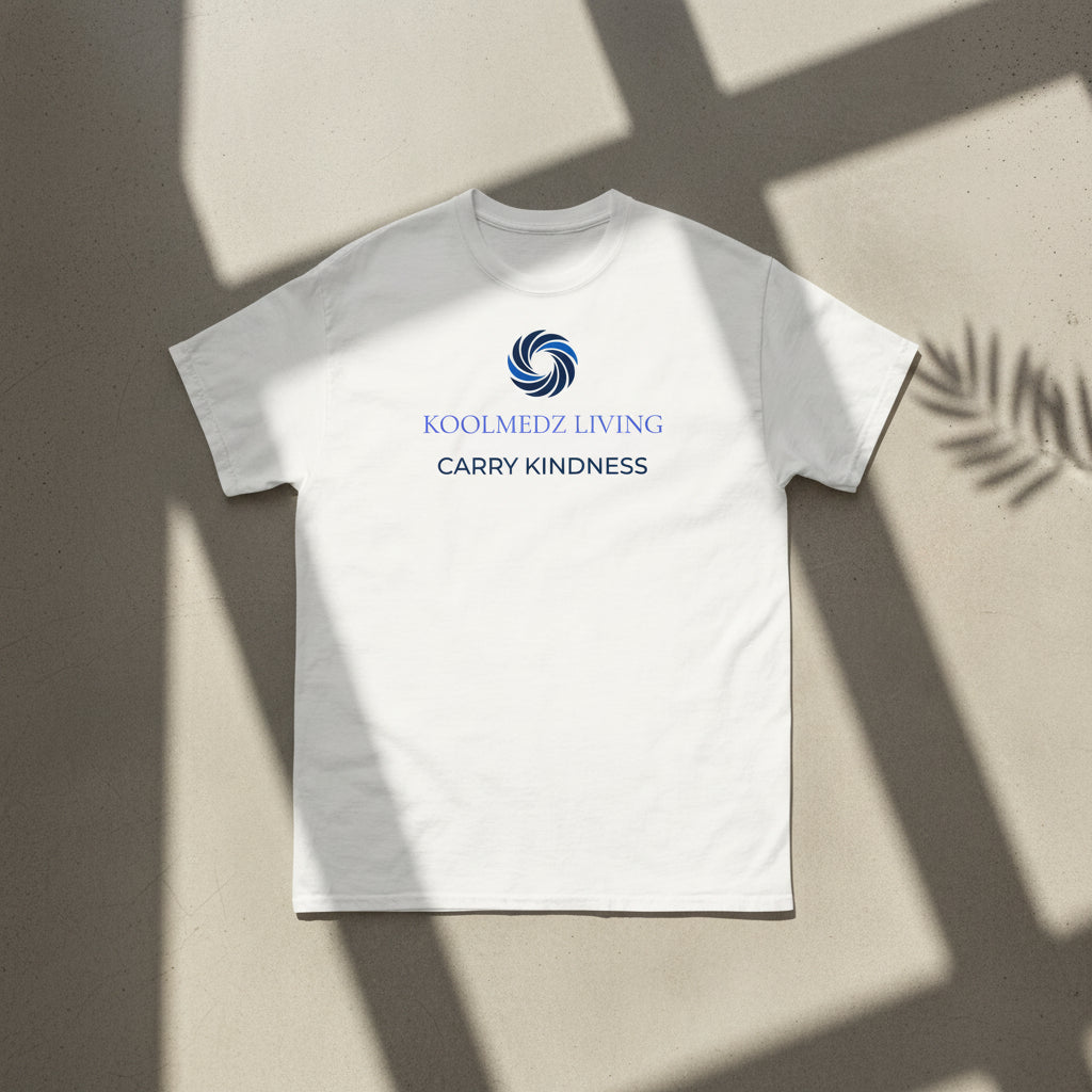 An off-white short-sleeve crewneck t-shirt with a blue and navy graphic on the chest. The graphic features a circular swirl logo above the text 'KOOLMEDZ LIVING' in blue and 'CARRY KINDNESS' in navy.
