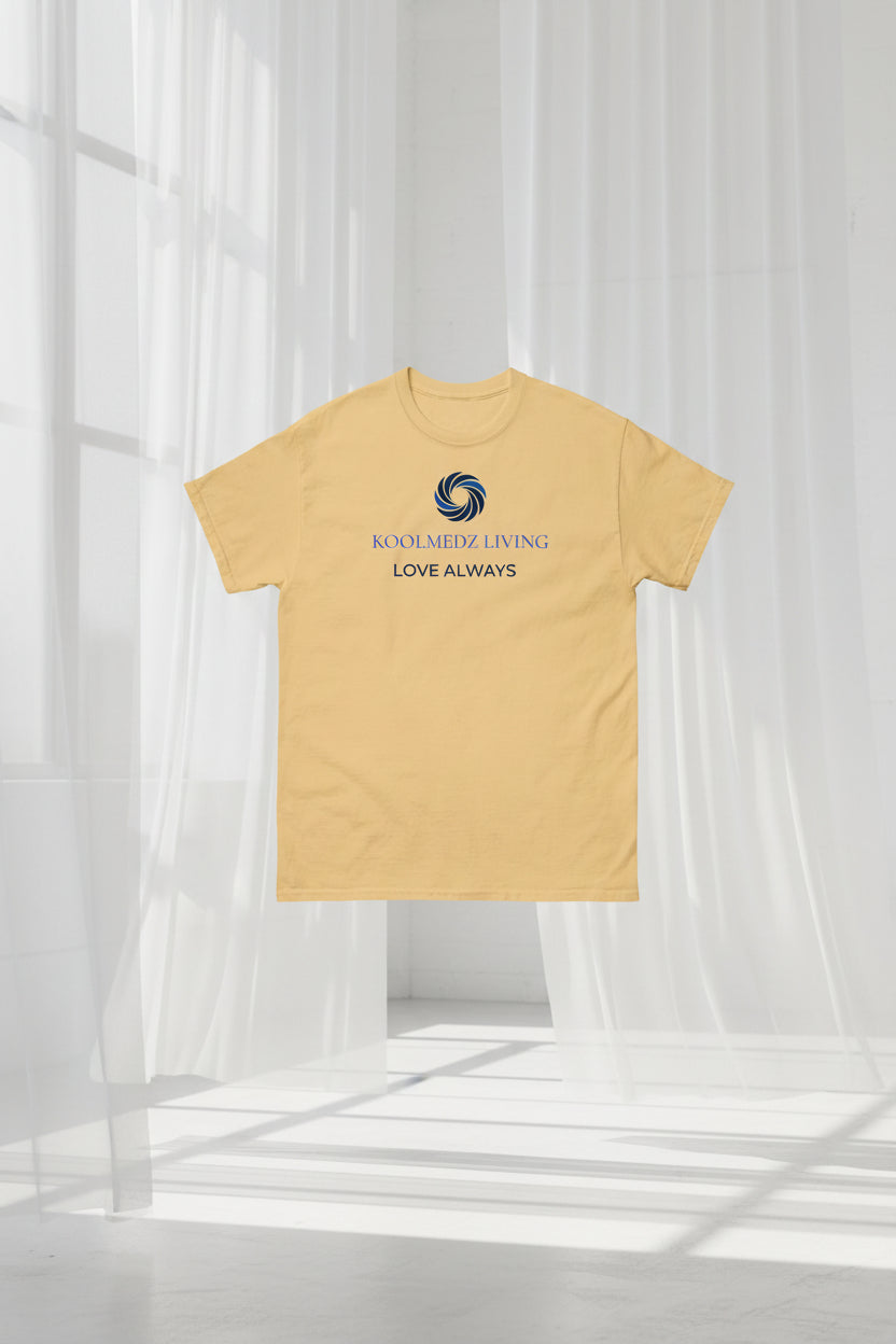 A light beige crewneck t-shirt with a blue and navy graphic on the chest featuring a swirl logo and the text 'KOOLMEDZ LIVING' and 'LOVE ALWAYS'.